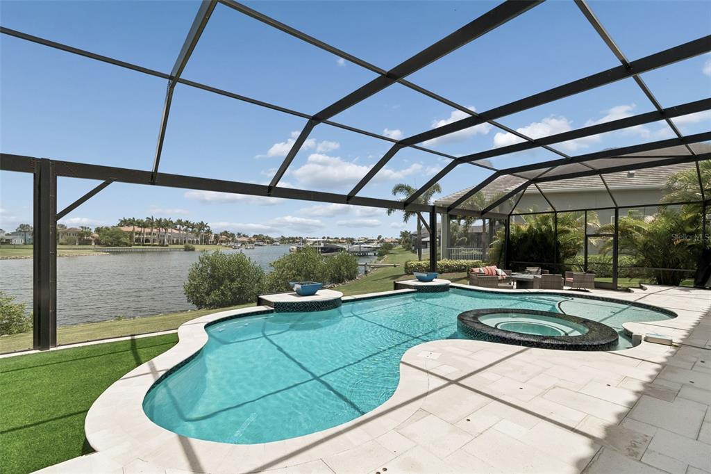 A swimming pool and spa with a screened-in enclosure overlooking a canal and palm trees — 823 MANNS HARBOR DRIVE, APOLLO BEACH, FL