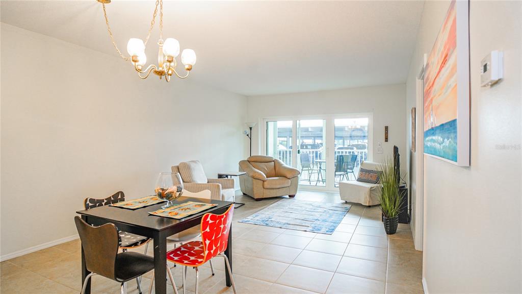 A living and dining area features a beige sofa, television console, and a round wooden table — 420 64TH AVENUE UNIT 101, ST PETE BEACH, FL