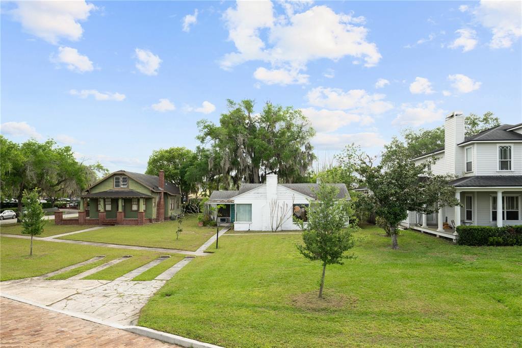 Three houses sit on a grassy lot with a brick driveway in the foreground — 240 KILLARNEY DRIVE, WINTER PARK, FL