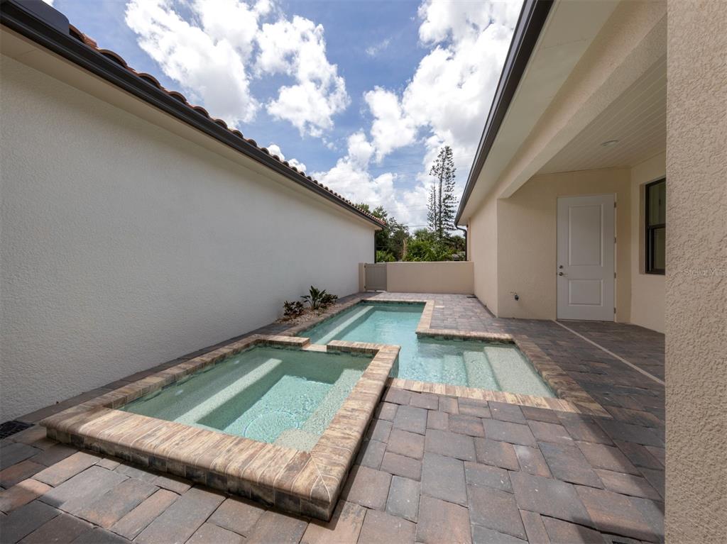 A small rectangular swimming pool and attached spa are surrounded by a paved patio area — 922 E VENICE AVENUE, VENICE, FL