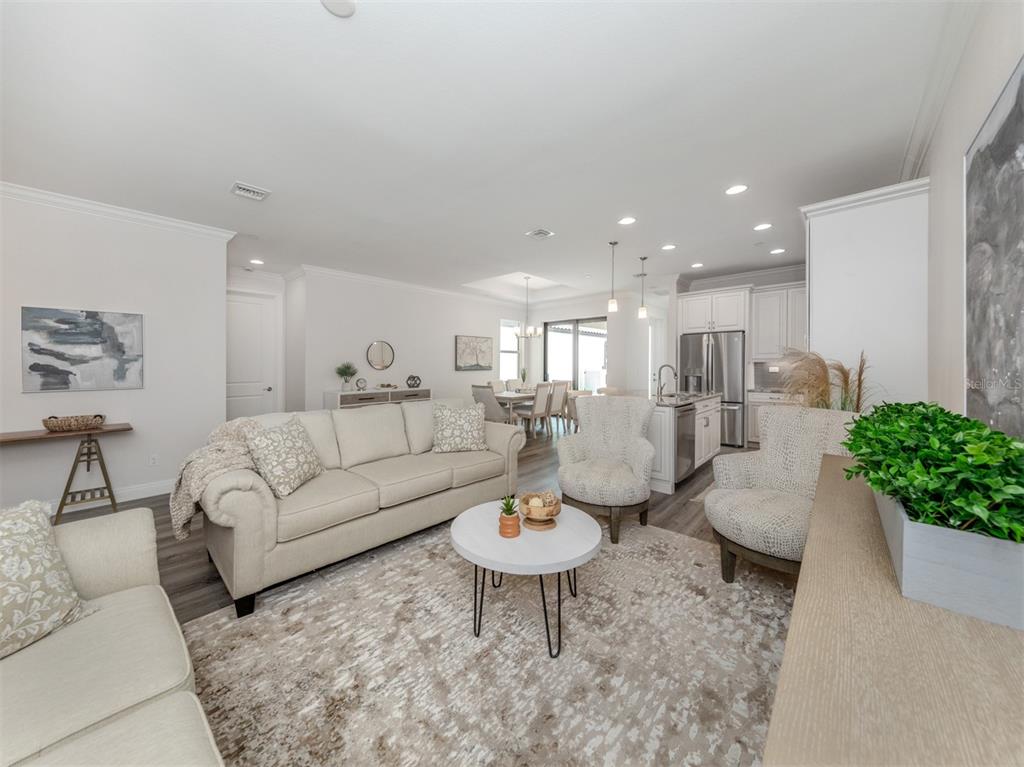A bright, open-concept living room features neutral furniture, a round coffee table, and a kitchen — 922 E VENICE AVENUE, VENICE, FL