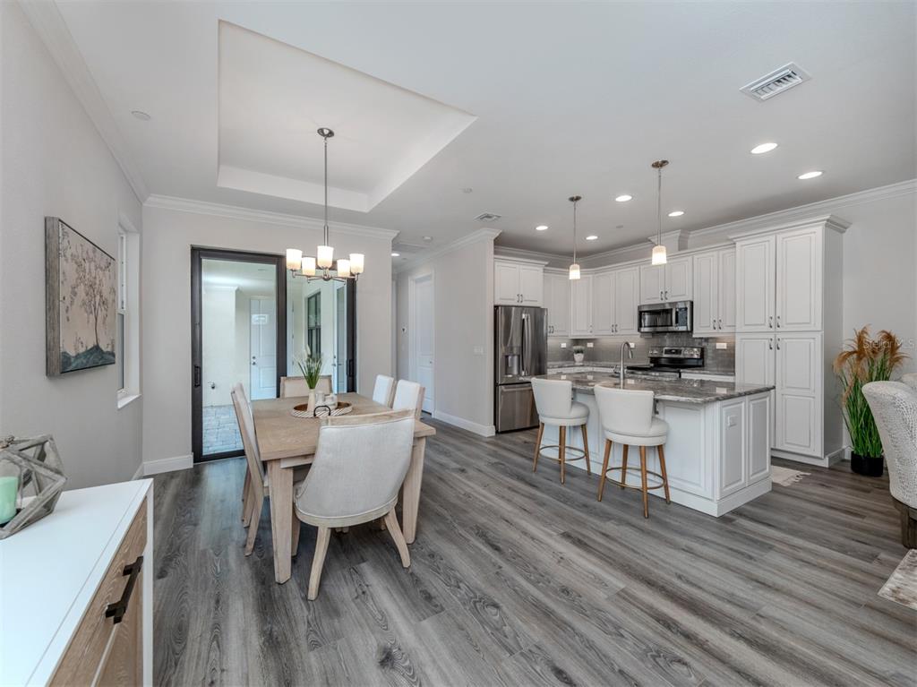 An open-concept kitchen and dining area features white cabinetry, a kitchen island, and wood flooring — 922 E VENICE AVENUE, VENICE, FL