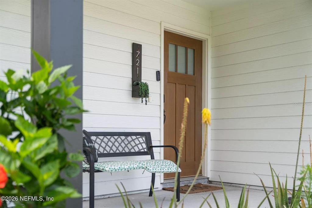 A front porch features a wooden door, a metal bench, and a vertical house number sign — 721 N VOLUSIA STREET, ST AUGUSTINE, FL