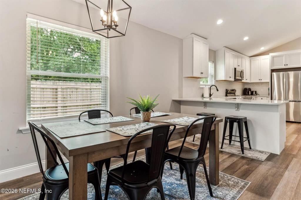 A dining area with a wooden table and black chairs sits adjacent to a kitchen — 721 N VOLUSIA STREET, ST AUGUSTINE, FL