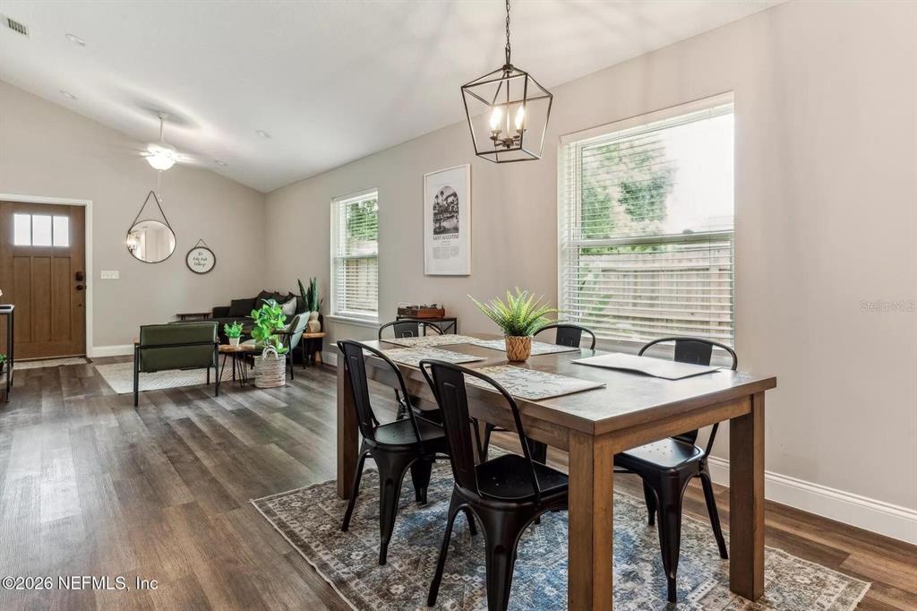 A dining area with a wooden table and black chairs sits beside a living room — 721 N VOLUSIA STREET, ST AUGUSTINE, FL