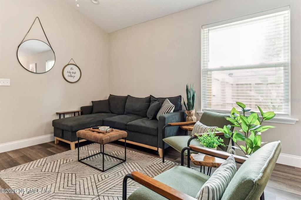 A living room features a dark sectional sofa, two green armchairs, and a geometric area rug — 721 N VOLUSIA STREET, ST AUGUSTINE, FL