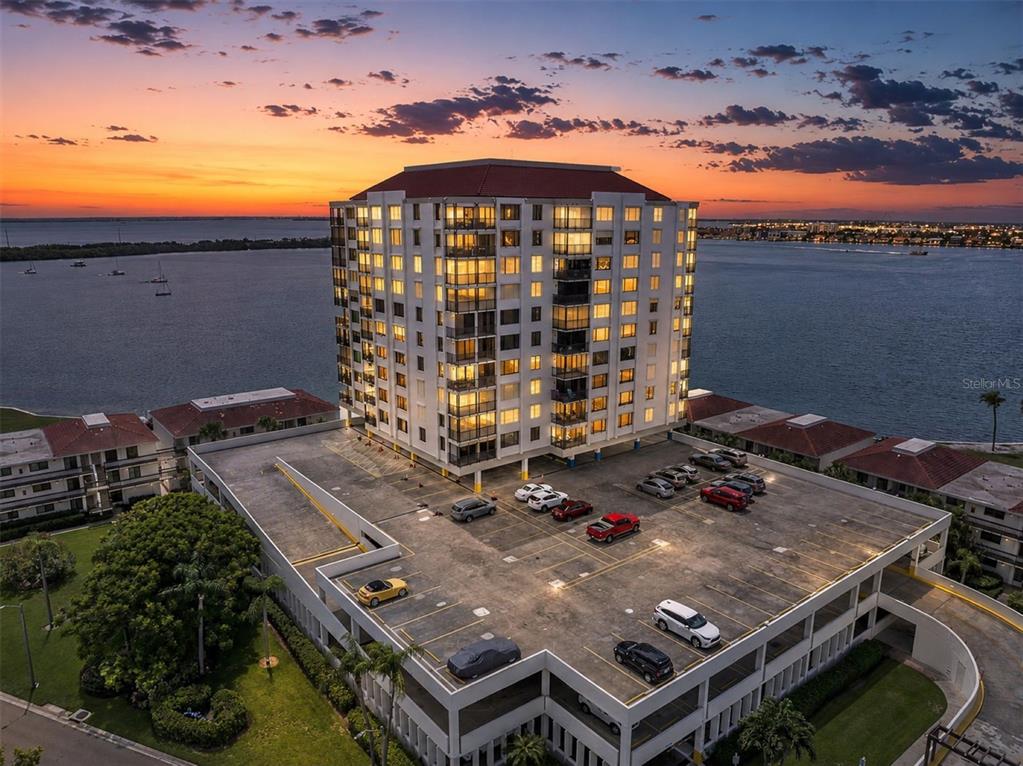 An aerial view shows a multi-story residential building complex surrounded by water and a bridge — 6287 BAHIA DEL MAR CIRCLE UNIT 401, ST PETERSBURG, FL