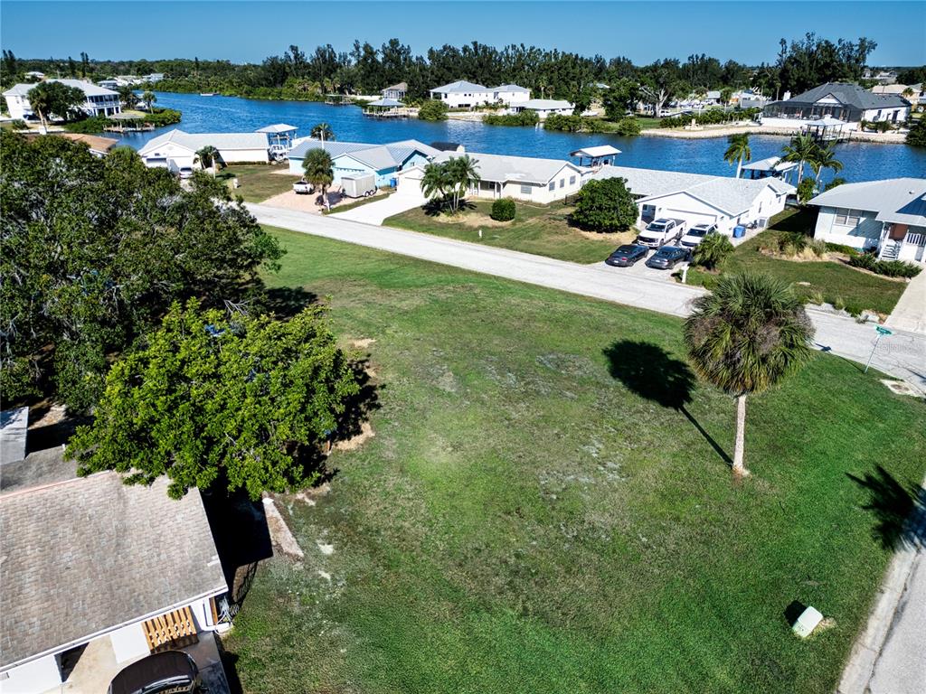 An aerial view shows a vacant grassy lot situated near a canal with surrounding houses — SABLE COVE, RUSKIN, FL