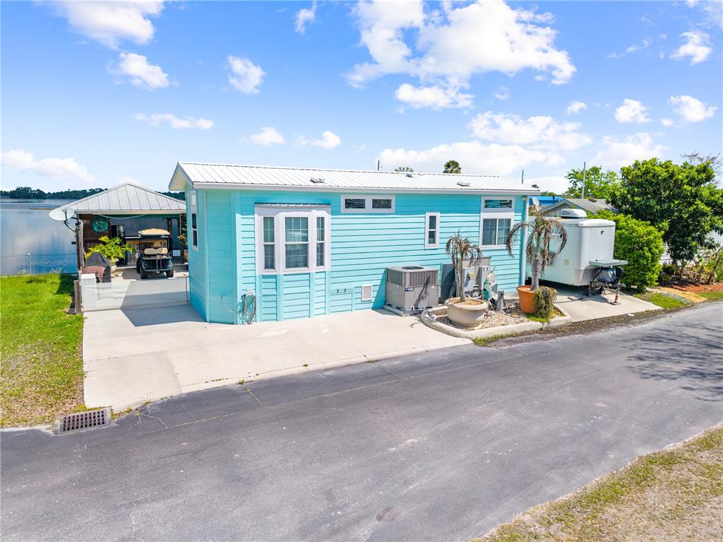 A light blue mobile home sits on a concrete pad next to a lake — 1315 PINE ISLAND DR N, ST CLOUD, FL