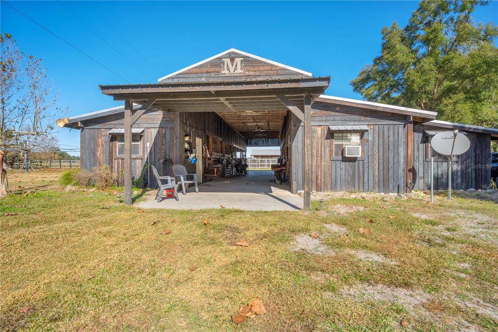 A rustic wooden barn with a central breezeway and a covered front porch — 17885 NE 2ND PLACE, WILLISTON, FL