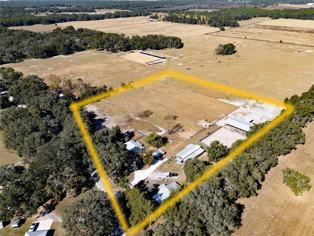 An aerial view shows a rural property with several buildings, fenced pastures, and mature trees — 17885 NE 2ND PLACE, WILLISTON, FL
