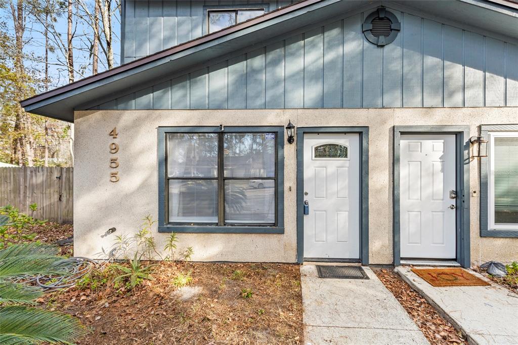 The exterior of a two-story townhouse features blue vertical siding, stucco walls, and two doors — 4955 KNIGHTSBRIDGE CIRCLE N, JACKSONVILLE, FL