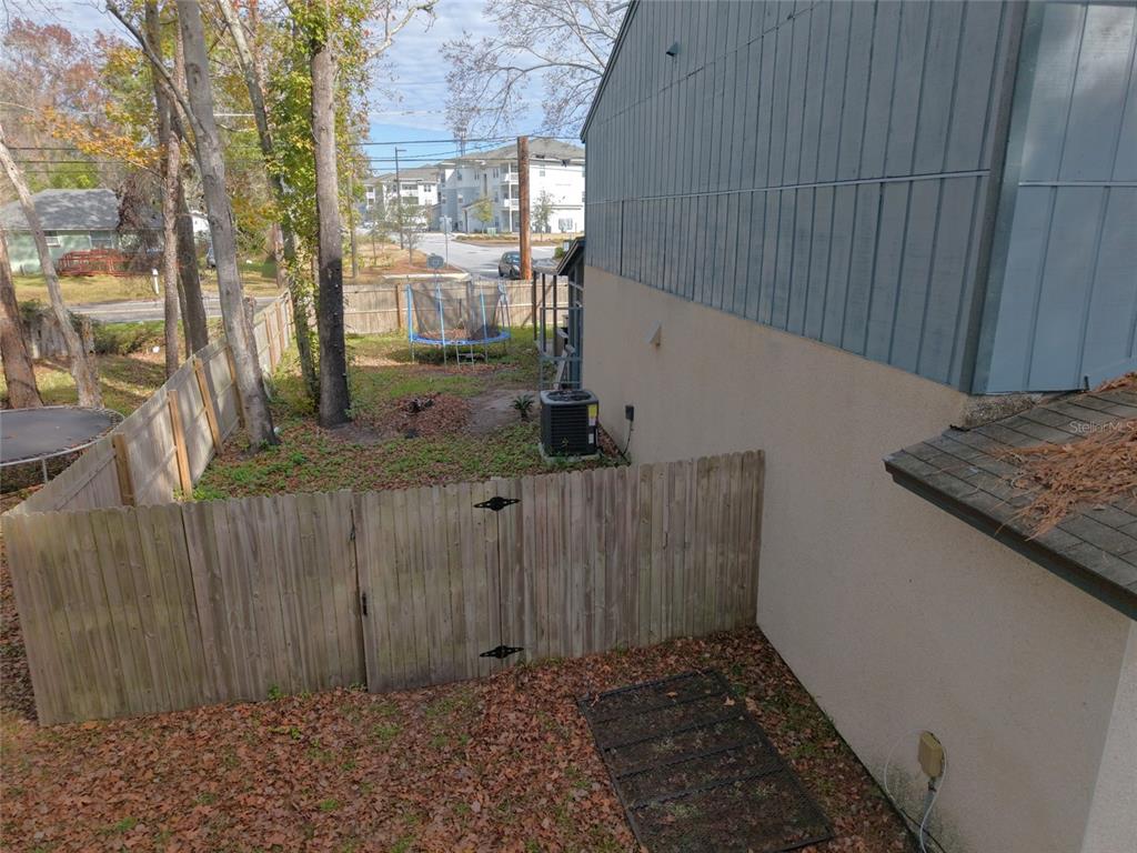 A view of a fenced backyard with a trampoline, trees, and an exterior wall — 4955 KNIGHTSBRIDGE CIRCLE N, JACKSONVILLE, FL