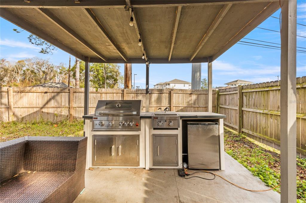 An outdoor kitchen with a stainless steel grill and refrigerator sits under a covered patio — 4955 KNIGHTSBRIDGE CIRCLE N, JACKSONVILLE, FL