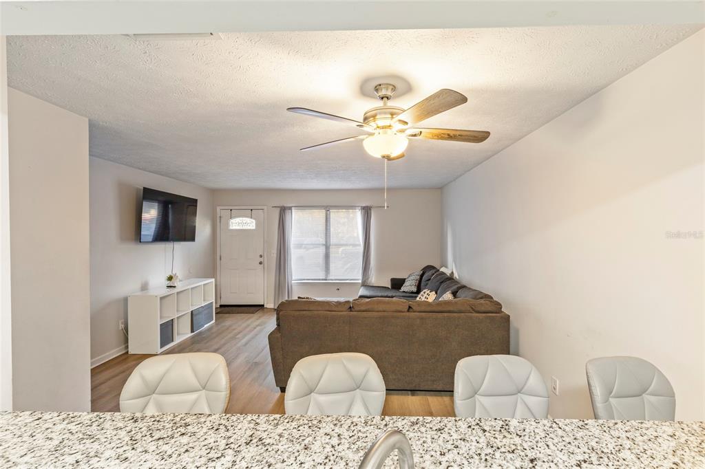 A living room with a sectional sofa, ceiling fan, and white storage unit near a door — 4955 KNIGHTSBRIDGE CIRCLE N, JACKSONVILLE, FL