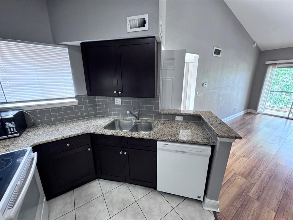 A kitchen features dark cabinets, granite countertops, a double sink, and a white dishwasher — 1916 LAKE ATRIUMS CIRCLE UNIT 33, ORLANDO, FL