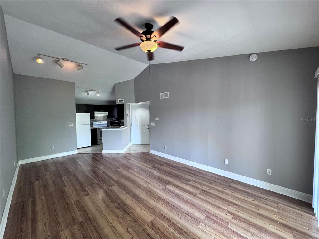 An open-concept living area features wood-look flooring, a vaulted ceiling with a fan, and a kitchen — 1916 LAKE ATRIUMS CIRCLE UNIT 33, ORLANDO, FL
