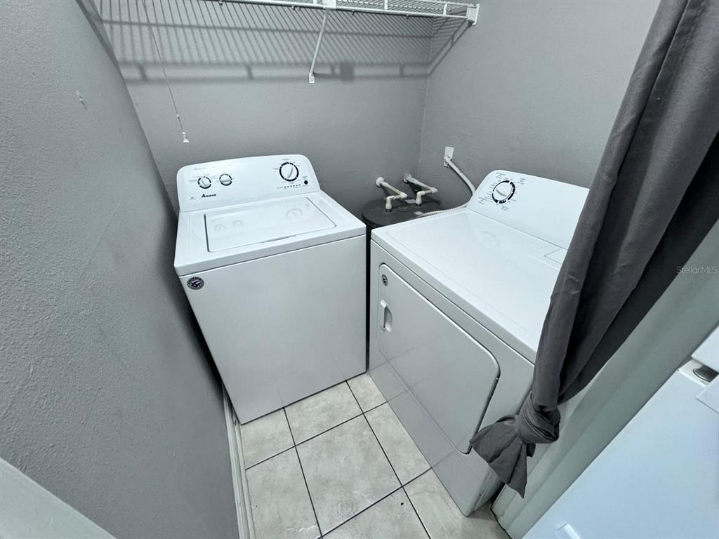 A laundry room features a white top-load washer and dryer on a tiled floor — 1916 LAKE ATRIUMS CIRCLE UNIT 33, ORLANDO, FL