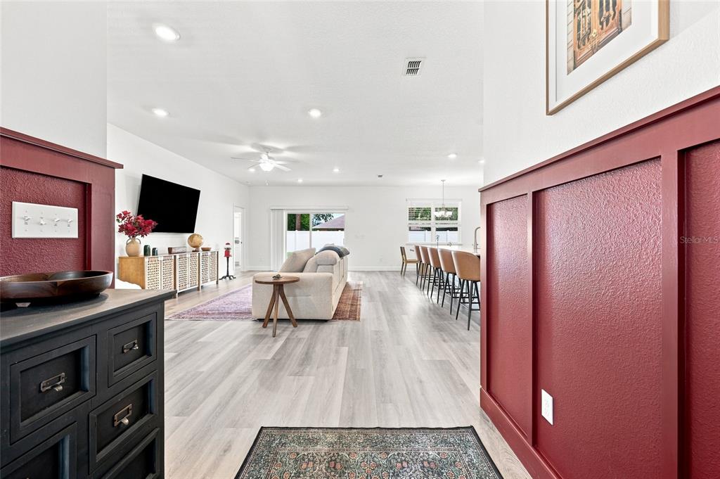 A view from a hallway into an open-concept living room with red wainscoting — 5 PINE BUSH LANE, PALM COAST, FL