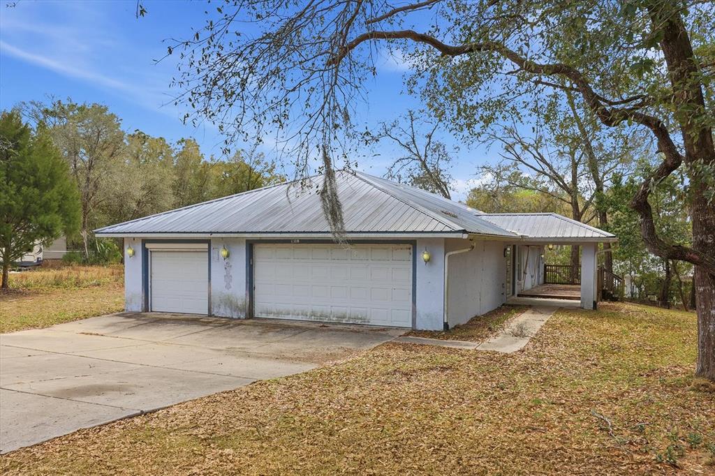 A single-story house with a metal roof and a three-car garage sits on a lot — 5120 E HOPP LANE, INVERNESS, FL
