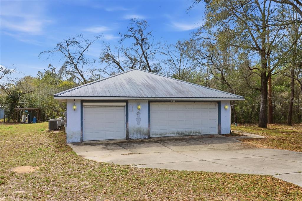 A detached two-car garage with a metal roof sits on a grassy lot — 5120 E HOPP LANE, INVERNESS, FL