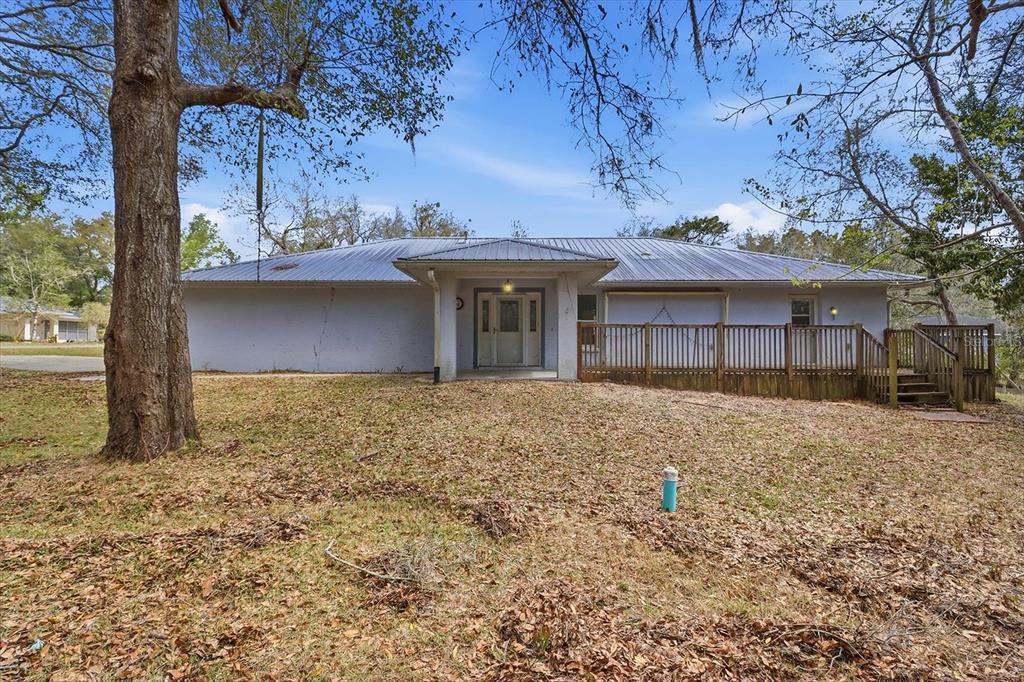 A single-story house with a metal roof, a wooden deck, and a front entrance — 5120 E HOPP LANE, INVERNESS, FL