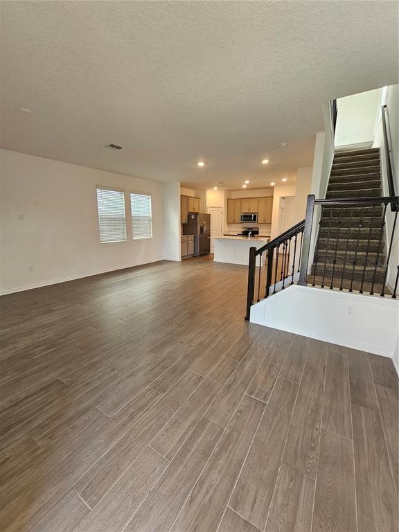 An open-concept living area features wood-look tile flooring, a kitchen with light cabinets, and stairs — 4123 CONJUNCTION WAY, APOPKA, FL