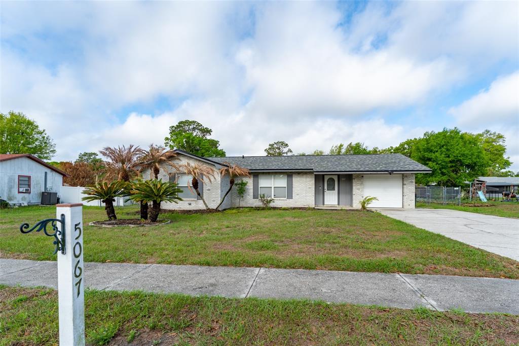 A single-story brick house with a garage and a front lawn under a cloudy sky — 5067 BLACK BIRCH TRAIL, MULBERRY, FL