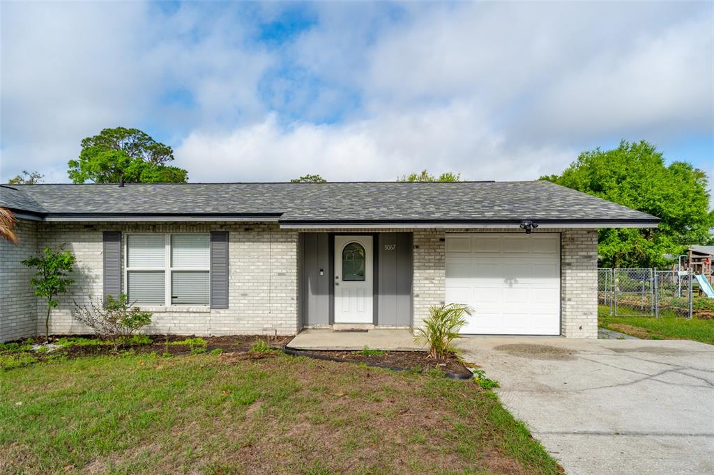 A single-story house with a light brick exterior, a white garage door, and a front entrance — 5067 BLACK BIRCH TRAIL, MULBERRY, FL