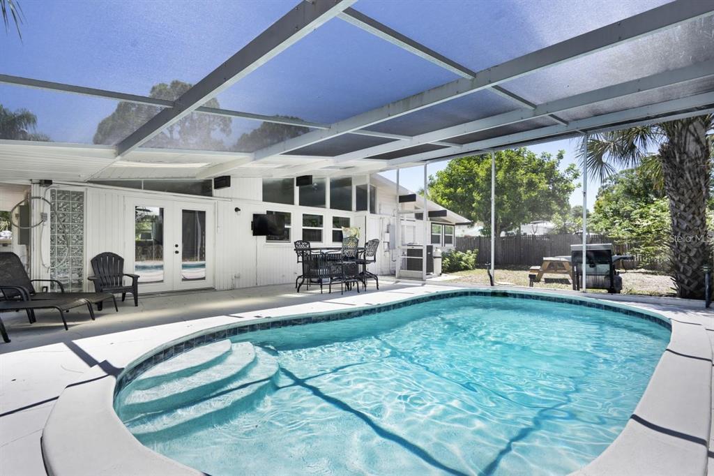 A screened-in patio features a swimming pool with built-in steps and outdoor dining furniture — 2213 WASON ROAD, SARASOTA, FL