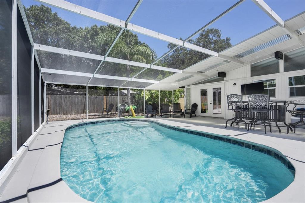 A screened-in patio features a swimming pool, outdoor furniture, and a white exterior wall — 2213 WASON ROAD, SARASOTA, FL