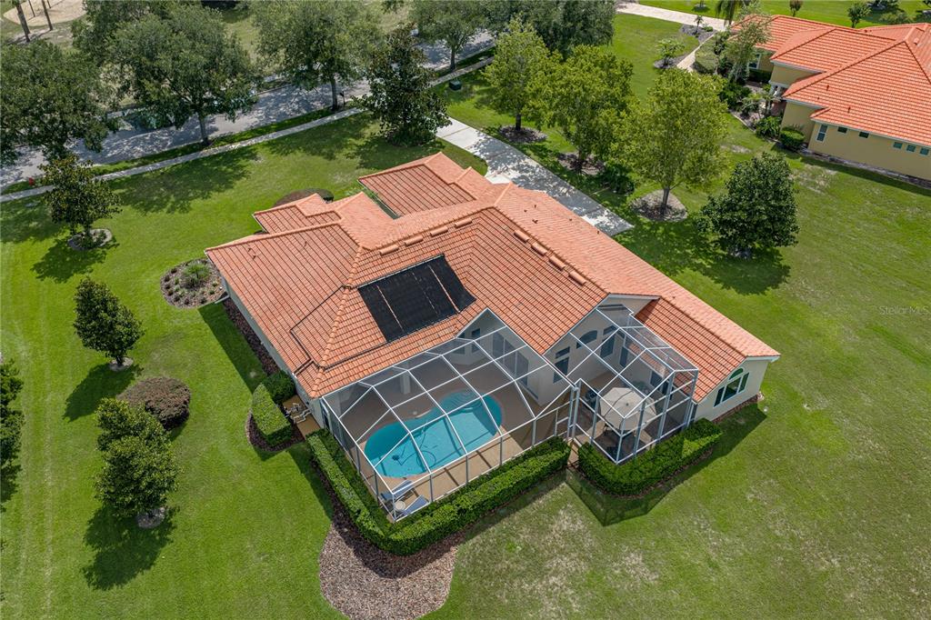 An aerial view of a house with a tile roof, pool cage, and solar panels — 19616 AMAZON BASIN BEND, LUTZ, FL