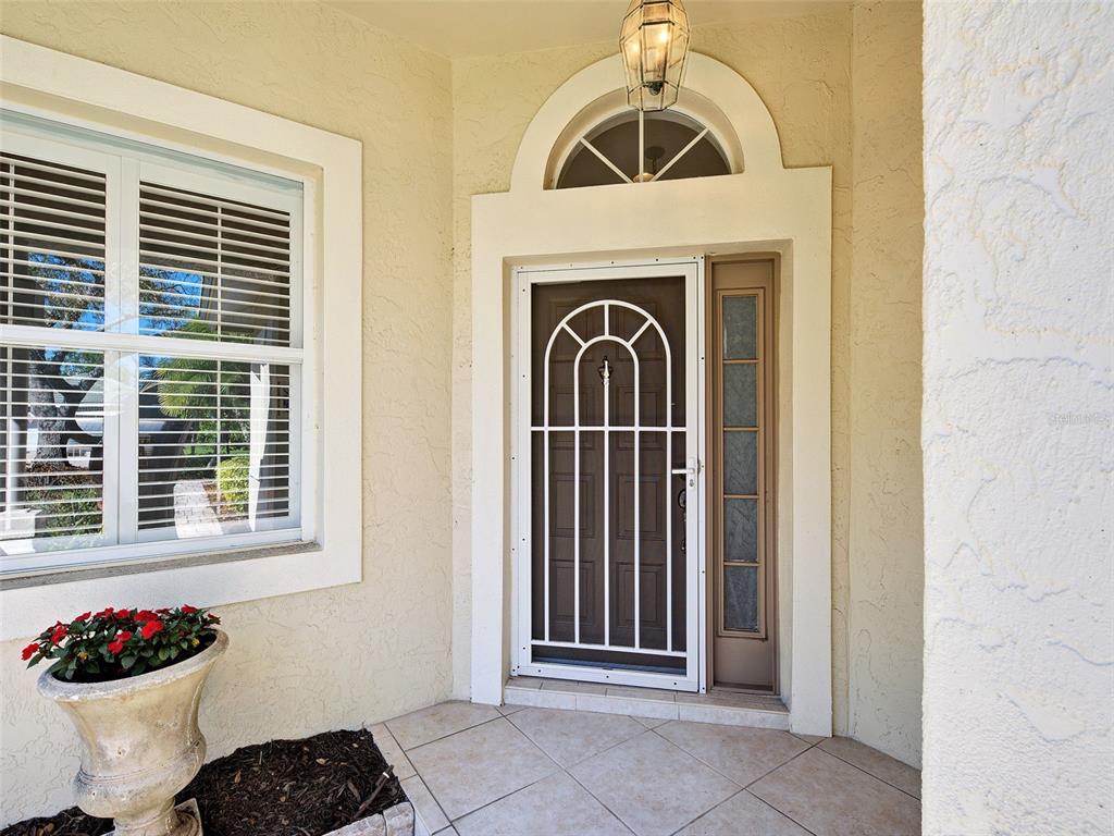 A front entryway features a white security door, a sidelight, and a potted plant — 311 LANSBROOK DRIVE, VENICE, FL