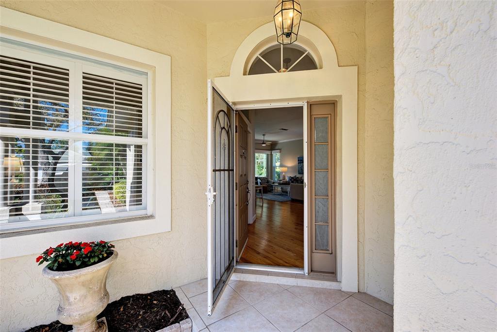 A front entryway features a tiled porch, a potted plant, and an open door — 311 LANSBROOK DRIVE, VENICE, FL