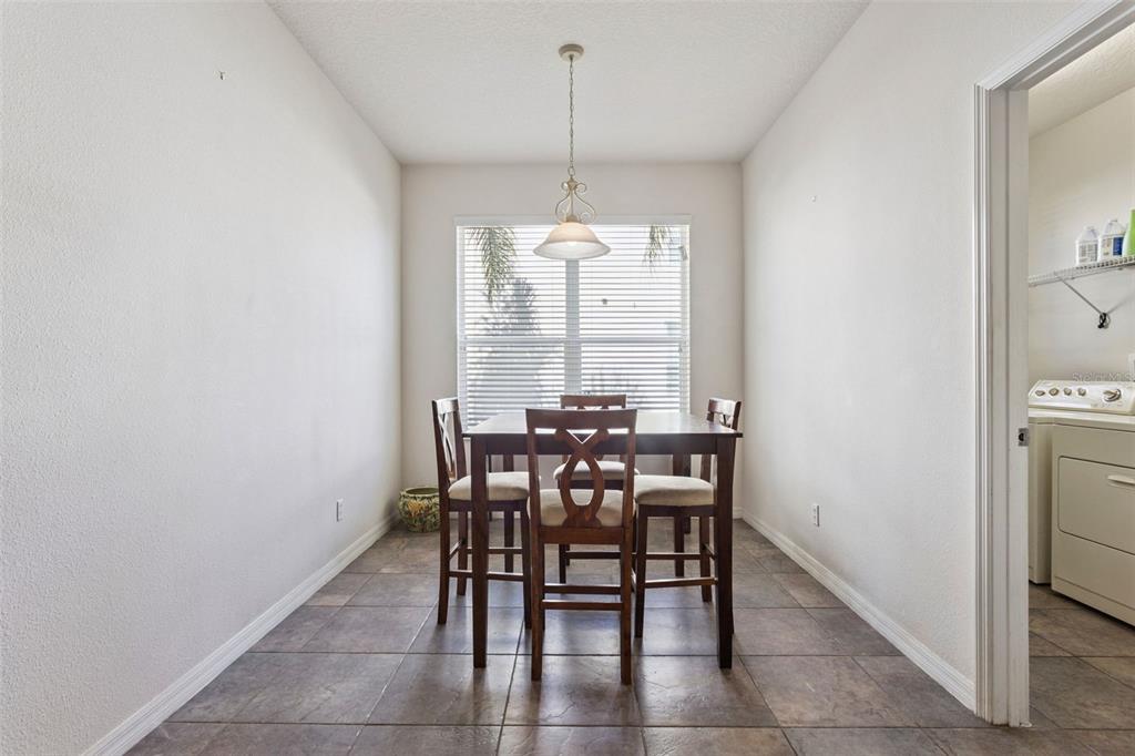 A dining area features a wooden table with four chairs, tile flooring, and a pendant light — 30337 GIDRAN TERRACE, MOUNT DORA, FL