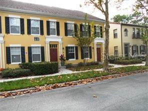 A yellow multi-story townhouse with dark shutters and a manicured hedge sits along a street — 705 CENTERVALE DRIVE, CELEBRATION, FL