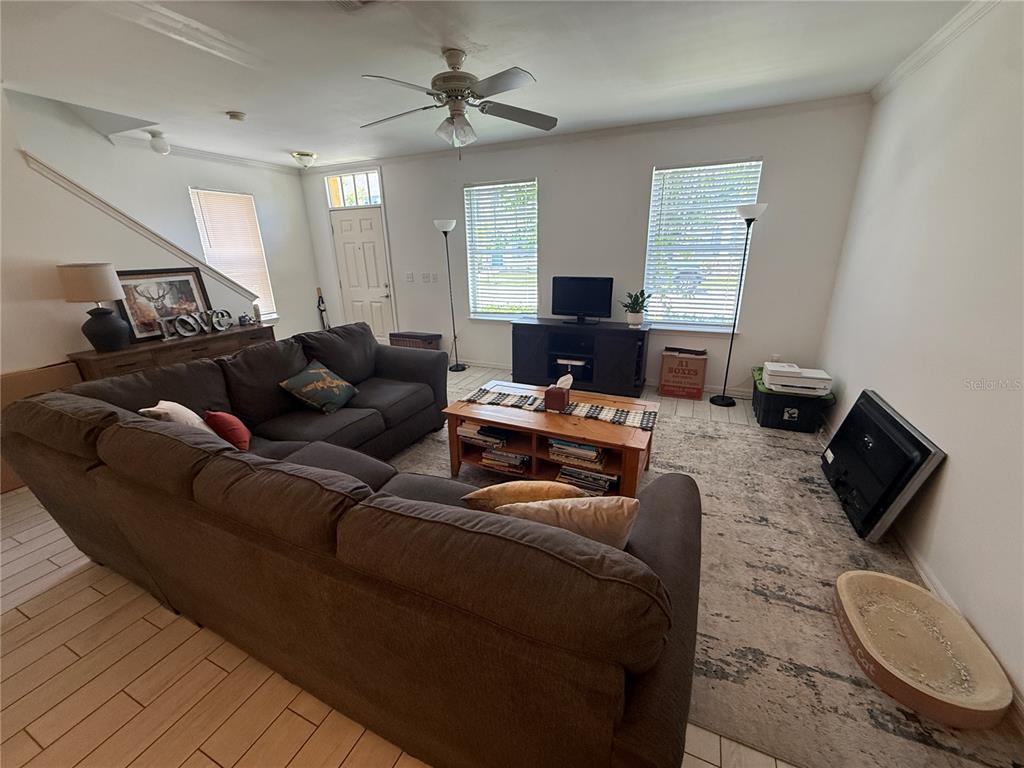 A living room features a large sectional sofa, a wooden coffee table, and tile flooring — 705 CENTERVALE DRIVE, CELEBRATION, FL
