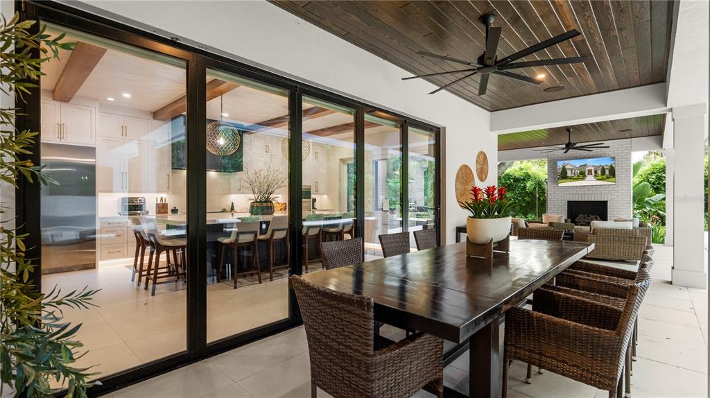 A covered outdoor dining patio features a dark wood ceiling, ceiling fan, and sliding glass doors — 2415 NEVADA ROAD, LAKELAND, FL