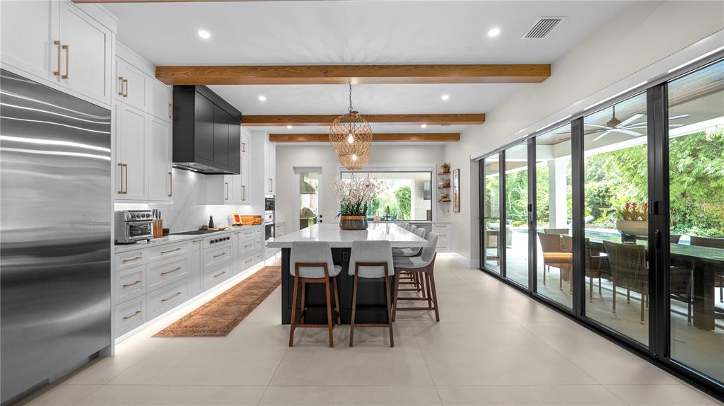 A modern kitchen features white cabinetry, a black island, wooden ceiling beams, and large sliding doors — 2415 NEVADA ROAD, LAKELAND, FL