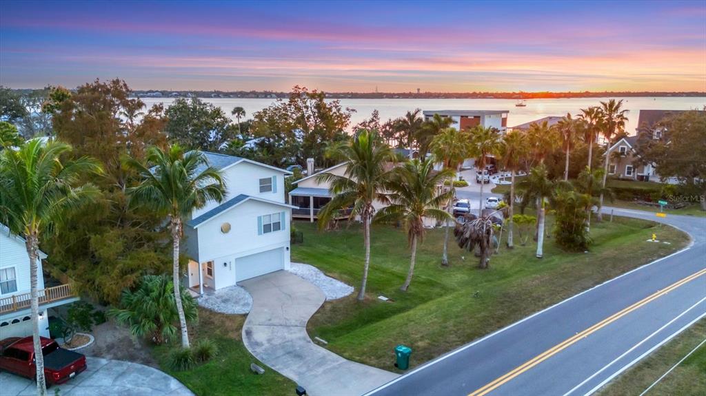 An aerial view of a two-story house with a driveway and palm trees near water — 3405 10TH STREET W, PALMETTO, FL