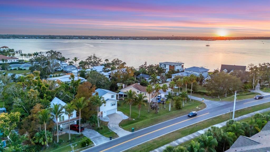 An aerial view of a coastal neighborhood with houses, palm trees, and a road at sunset — 3405 10TH STREET W, PALMETTO, FL