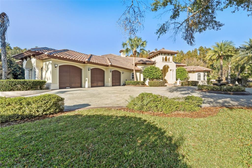 A large Mediterranean-style house with a three-car garage and a circular driveway — 19165 GERACI ROAD, LUTZ, FL