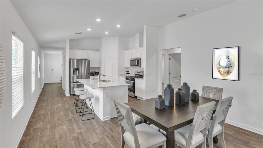 A kitchen with white cabinets and a dining area with a dark wood table — 17 DIVOT PLACE, BUNNELL, FL