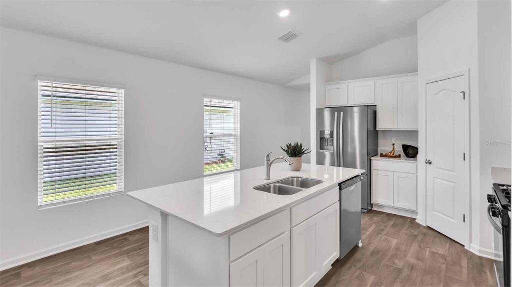A modern kitchen features white cabinets, a central island with a sink, and stainless appliances — 17 DIVOT PLACE, BUNNELL, FL