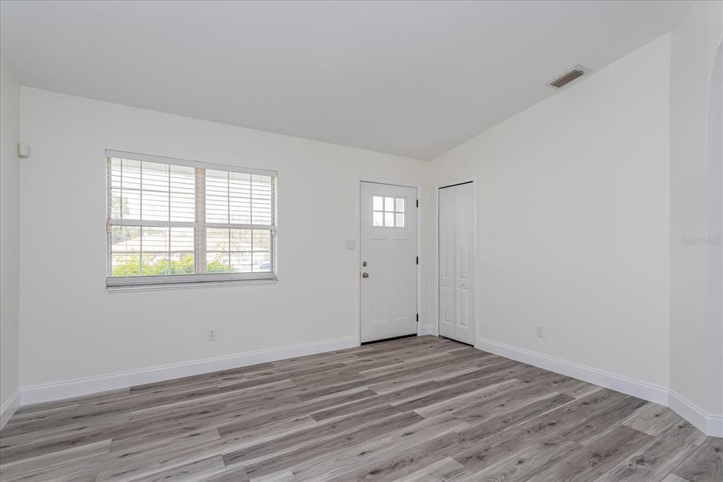 A room with white walls, wood-look flooring, a window with blinds, a door, and a closet — 414 TRANQUILLE OAKS DRIVE, OCOEE, FL