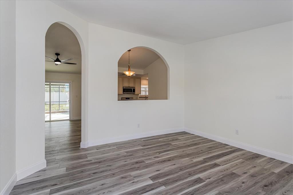 An empty room with wood-look flooring features an arched doorway and an arched wall cutout — 414 TRANQUILLE OAKS DRIVE, OCOEE, FL