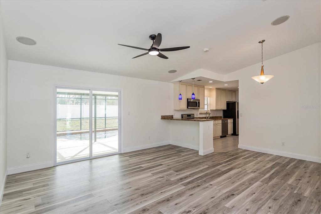 A living room with wood-look flooring opens to a kitchen with a breakfast bar — 414 TRANQUILLE OAKS DRIVE, OCOEE, FL
