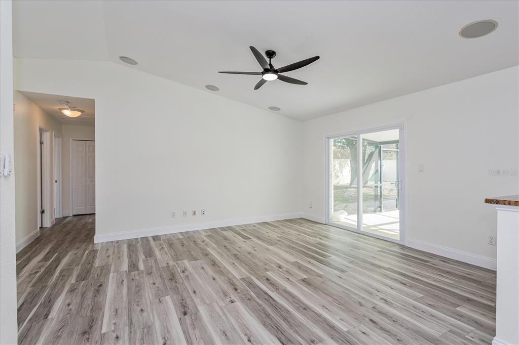 A living room features white walls, vaulted ceilings, a ceiling fan, and wood-look flooring — 414 TRANQUILLE OAKS DRIVE, OCOEE, FL