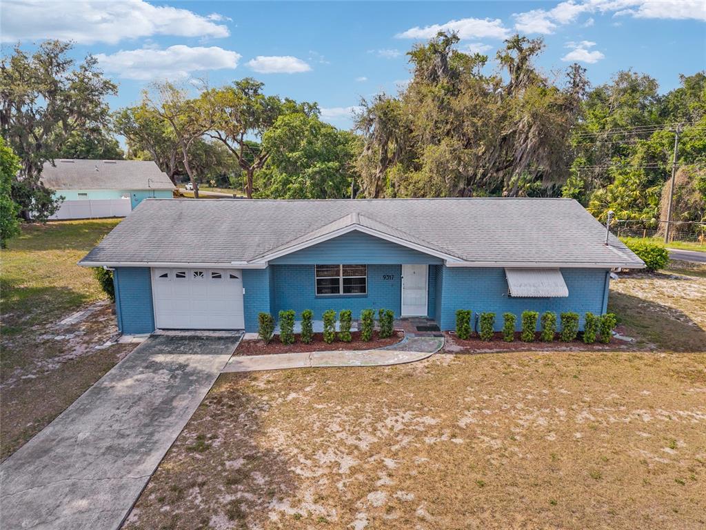A blue brick house with a white garage door and a gray shingled roof — 9317 E CRESCENT DRIVE, INVERNESS, FL