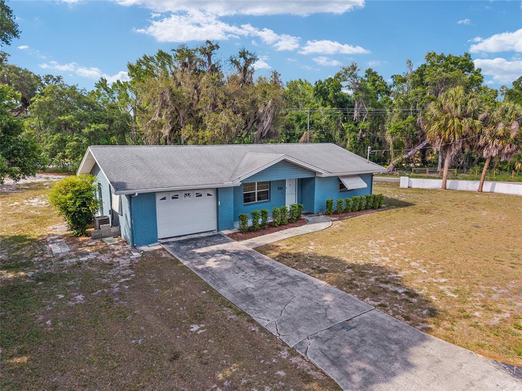 A blue brick single-story house features a white garage door and a concrete driveway — 9317 E CRESCENT DRIVE, INVERNESS, FL
